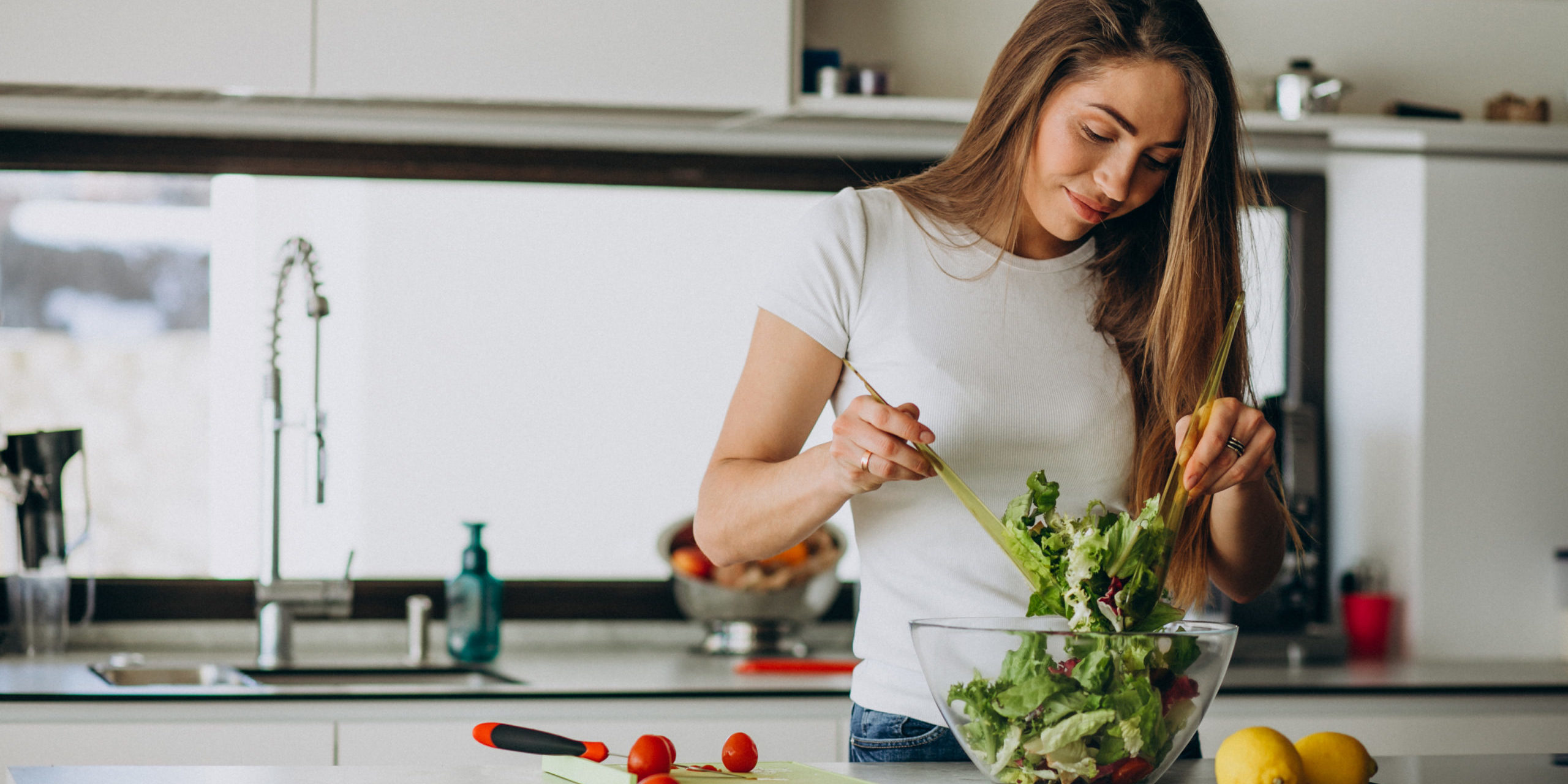 Young woman making salad at the kitchen