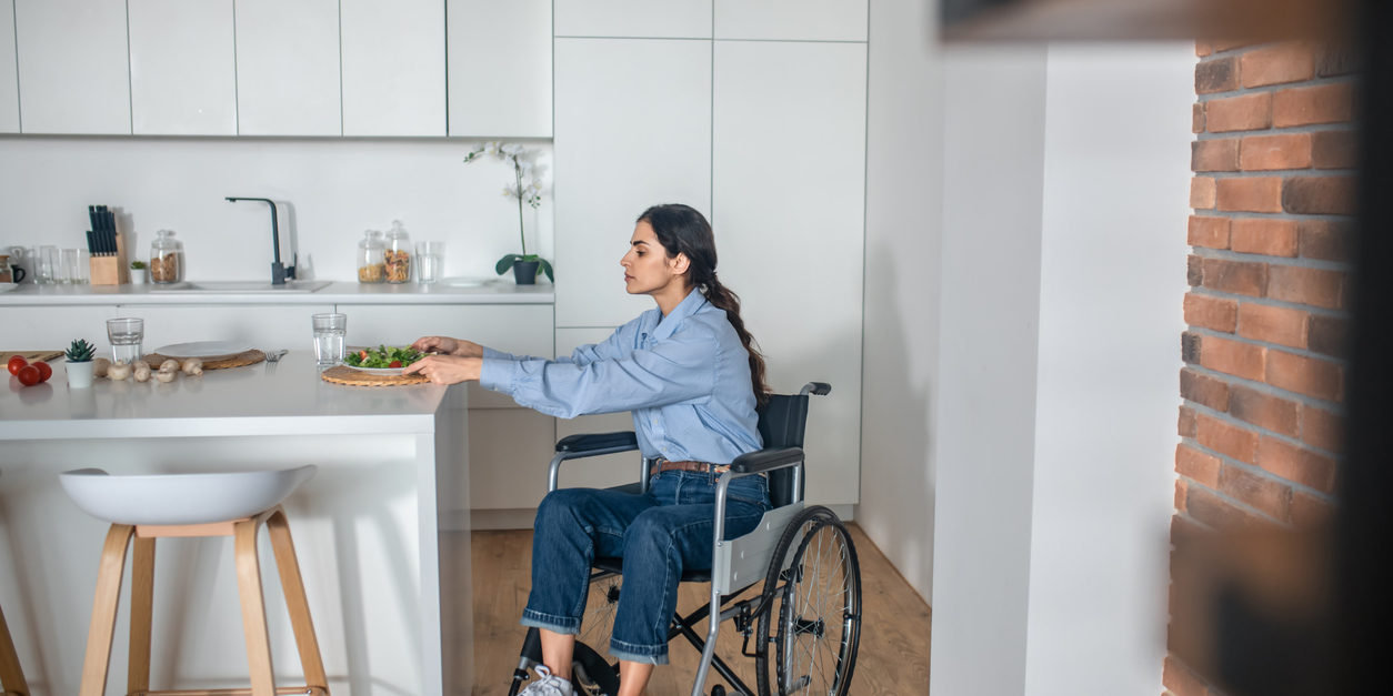A cute girl on a wheelchair in the kitchen at home