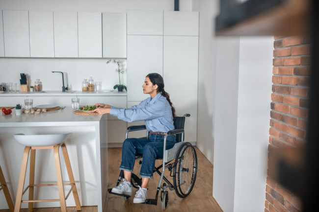 A cute girl on a wheelchair in the kitchen at home