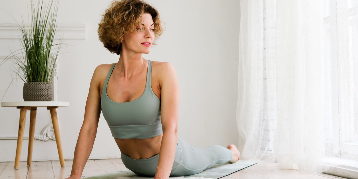 A young, beautiful, woman works out at home on a yoga mat.