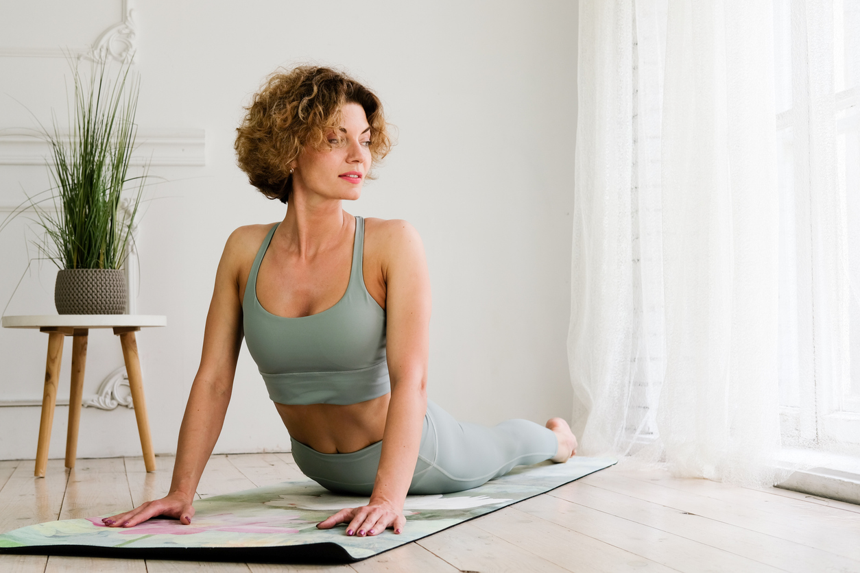 A young, beautiful, woman works out at home on a yoga mat.